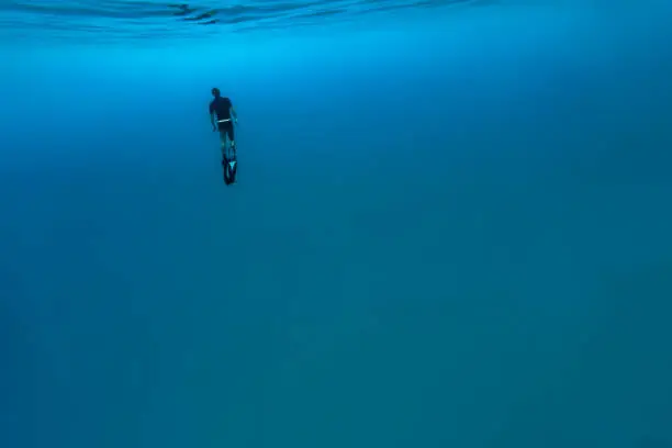 A DSLR Canon underwater photo of a 41-year-old Brazilian man free diving into clear turquoise water at Baía do Sancho in Fernando de Noronha, Pernambuco, Brazil.