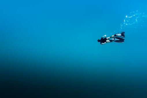 A DSLR Canon underwater photo of a 41-year-old Brazilian man free diving into clear turquoise water at Baía do Sancho in Fernando de Noronha, Pernambuco, Brazil.