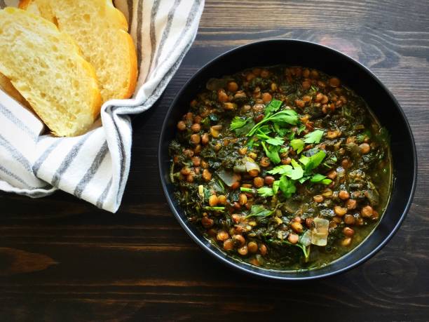 Spinach and Lentil Soup with Bread A bowl of spinach and lentil soup with slices of bread on the side shown on a dark wood background soup lentil healthy eating dishware stock pictures, royalty-free photos & images