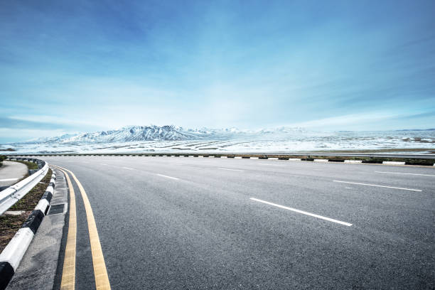 istock empty asphalt road with snow mountains in blue sky 849004674
