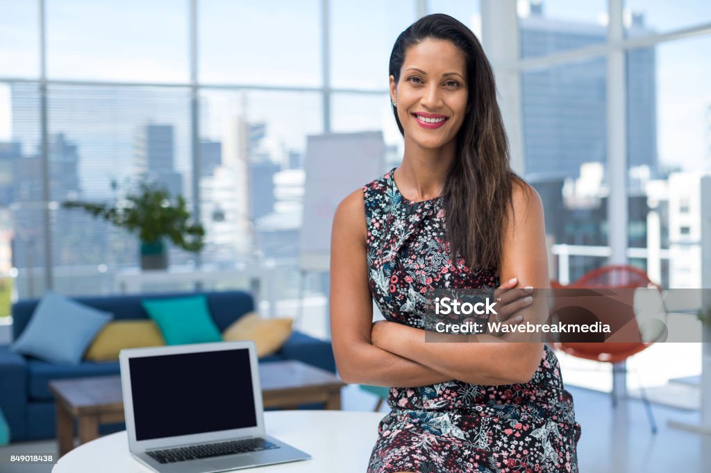 Female executive sitting with arms crossed on desk Female executive sitting with arms crossed on desk in the office One Woman Only Stock Photo