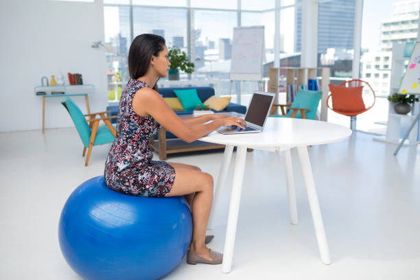 istock Female executive using laptop while sitting on exercise ball at desk 849020636