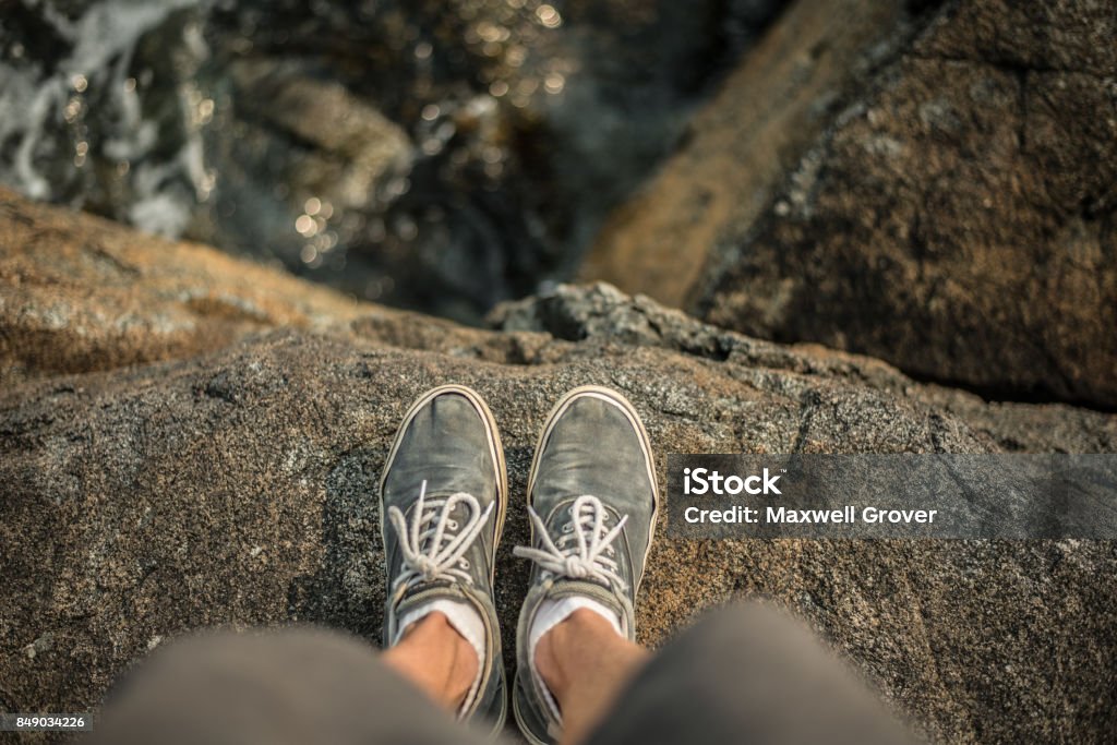 Shoes standing on the edge of cliff over ocean Photo Taken at campfire rock on Keats Island, British Columbia, Canada. Cliff Stock Photo