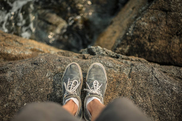 Shoes standing on the edge of cliff over ocean Photo Taken at campfire rock on Keats Island, British Columbia, Canada. ravine stock pictures, royalty-free photos & images