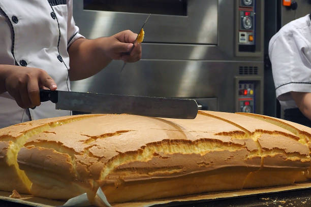 Chef with knife on hand cutting the enormous large chiffon cake