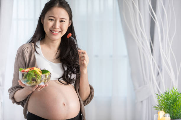 Asian pregnant woman on kitchen with healthy vegetable . stock photo