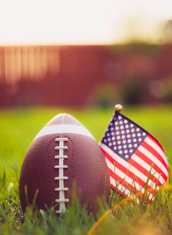 American Football in grass with American flag