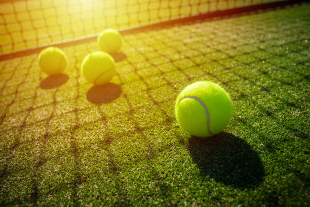 Tennis balls on grass court with sunlight