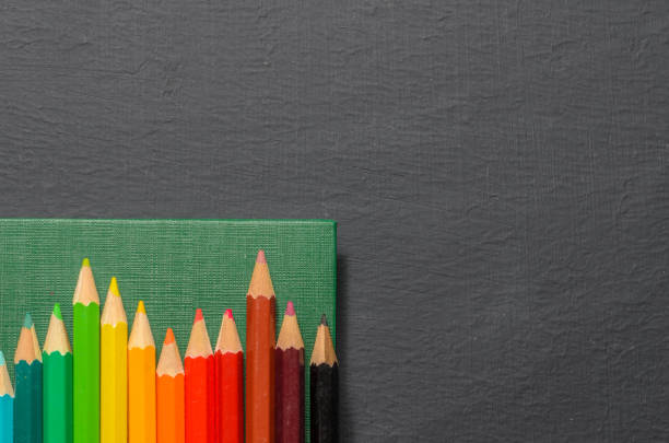istock Color pencils, notebook on black background, top view 849077752