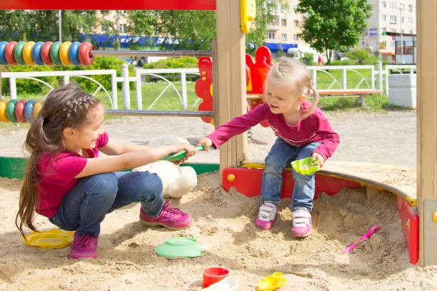 conflictos en el patio. dos niños peleando por un juguete en la sandbox - outdoor toy fotografías e imágenes de stock