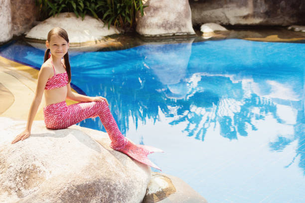 istock Mermaid girl with pink tail on rock at poolside 849092128