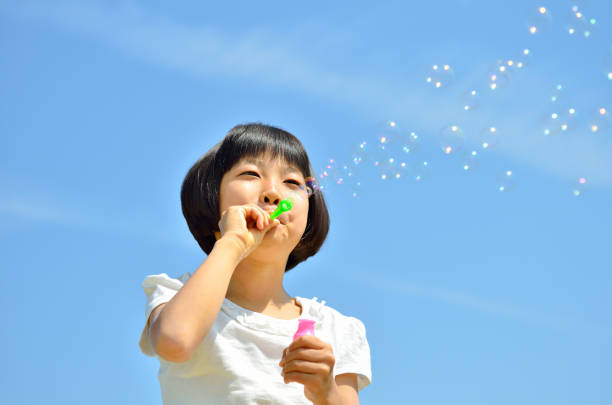 istock Girls blowing soap bubbles in the blue sky 849120562