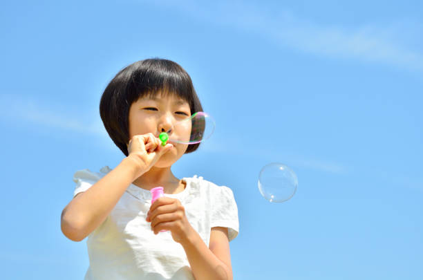 istock Girls blowing soap bubbles in the blue sky 849120566
