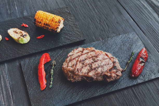 istock Grilled beef steak closeup on dark wooden table background 849125084