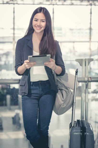 istock Young female passenger at the airport, using her tablet computer while waiting for her flight 849129068