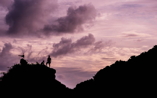 istock silhouette people climbing on cliff at twilight time, copy space. 849140062