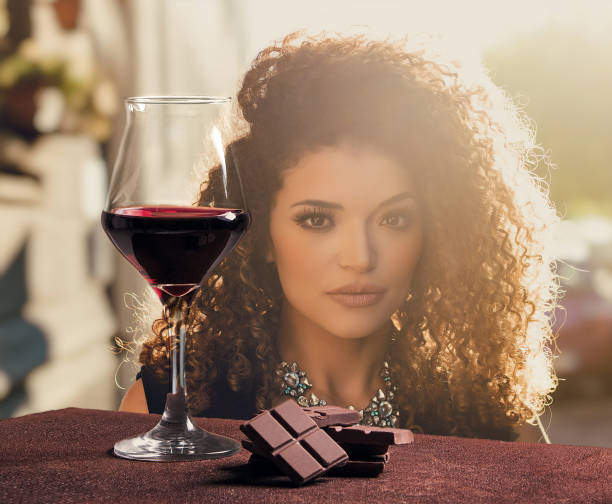 Red wine glass with chocolate and gorgeous woman portrait in sunlight Red wine glass with chocolate and gorgeous woman portrait in sunlight golden hour wine stock pictures, royalty-free photos & images