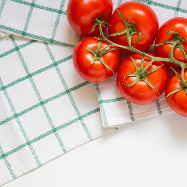 Fresh organic tomatoes on white kitchen towel, top view stock photo