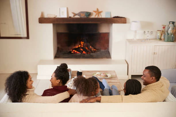 istock Family Sitting On Sofa In Lounge Next To Open Fire 849157964