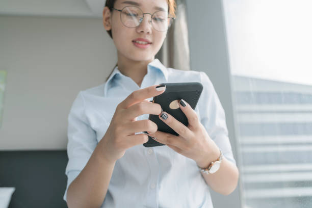 istock woman standing by window using smartphone 849158306