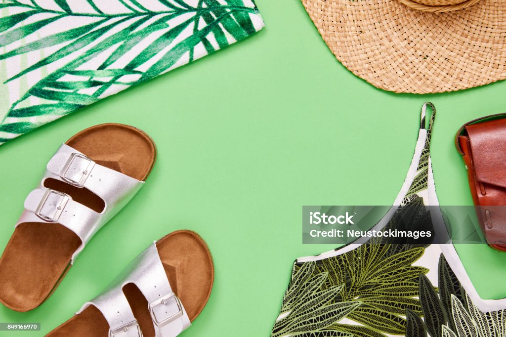 Overhead shot of top sandal sun hat and leather purse Flat lay shot of summer vacation accessories. Overhead shot of top sandal sun hat and leather purse. They are arranged on green background. Summer Stock Photo