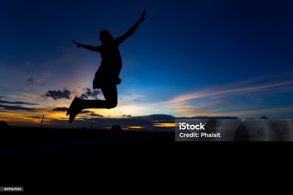 Silhouette of woman posing at sunset or sunrise Active Lifestyle Stock Photo