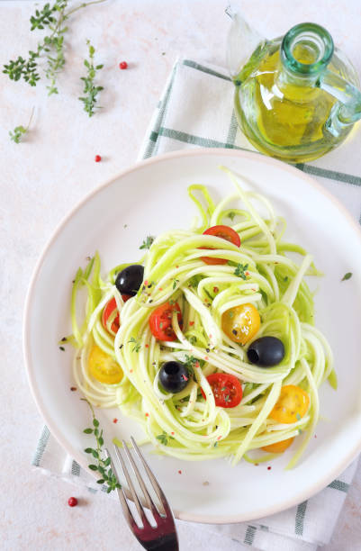 istock Raw food diet: uncooked spaghetti zucchini, cherry tomatoes, olives and olive oil 849177154