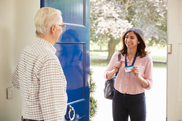 istock Senior man opens front door to young woman making home visit 849177716