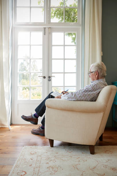 istock Senior man sitting in armchair doing  crossword 849178412