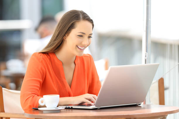 istock Lady in orange typing in a laptop in a restaurant 849181080