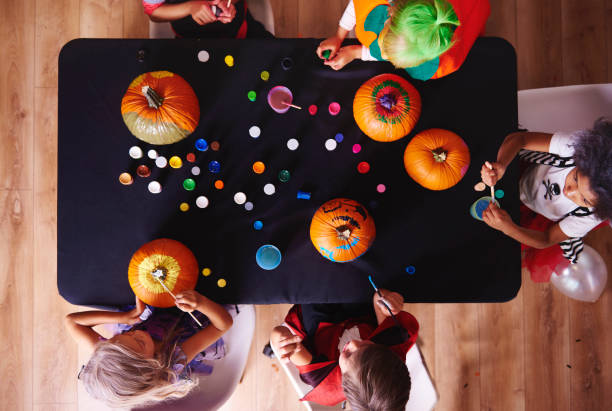 View from above kids painting pumpkins View from above kids painting pumpkins pumpkin decorating stock pictures, royalty-free photos & images