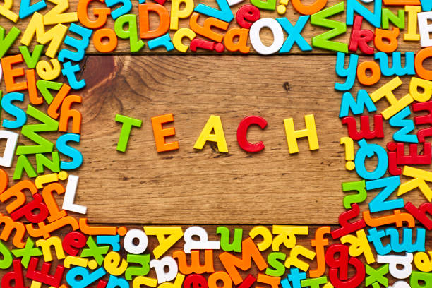 istock Overhead view of teach surrounded with colorful alphabets on wood 849181864