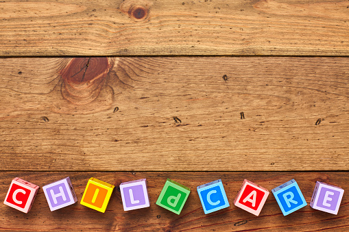Overhead view of colorful childcare blocks arranged on bottom of wood. Flat lay of multi colored alphabets on wooden background. Empty space on wood is for advertisement.