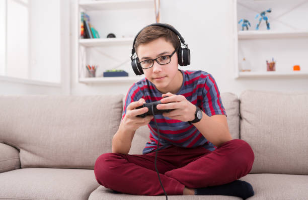 skoncentrowany nastoletni chłopiec gra w gry wideo w domu - playing video game little boys playful zdjęcia i obrazy z banku zdjęć