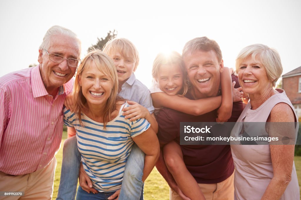 Família de geração multi no jardim sorriso para a câmera, close-up - Foto de stock de Família de várias gerações royalty-free