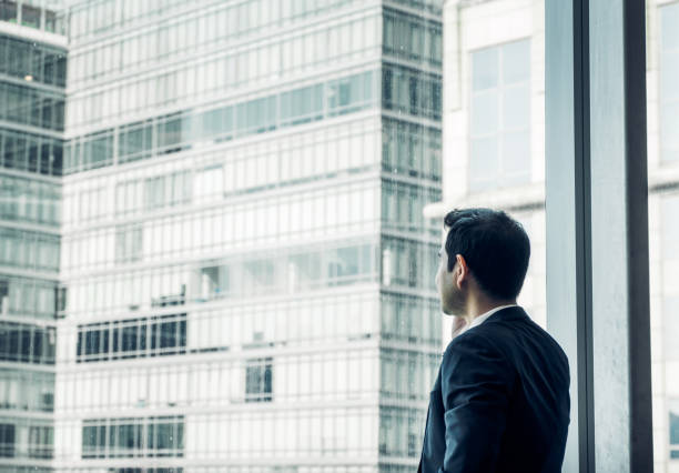 istock Businessman using mobile phone near office window at office building,communication concept,vintage filter 849192874