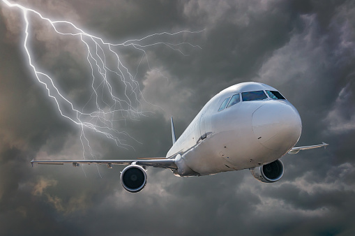 Airplane is flying in storm. Dark clouds and lightning in background.