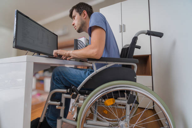 handicapped disabled man on wheelchair is working with computer in office. - physical impairment wheelchair disabled accessibility imagens e fotografias de stock