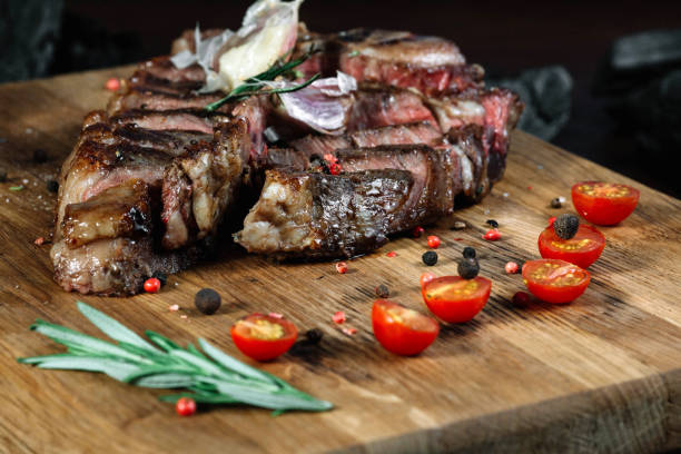 istock Sliced grilled T-bone steak tomatoes and on a cutting board on dark background 849196192