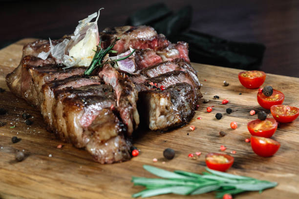 istock Sliced grilled T-bone steak tomatoes and on a cutting board on dark background 849196264