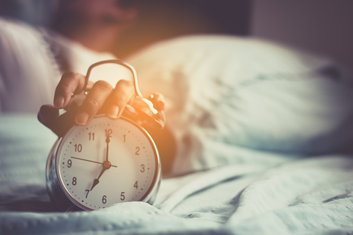 Clock on the bed in the morning.