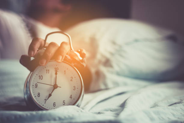 Clock on the bed in the morning. stock photo