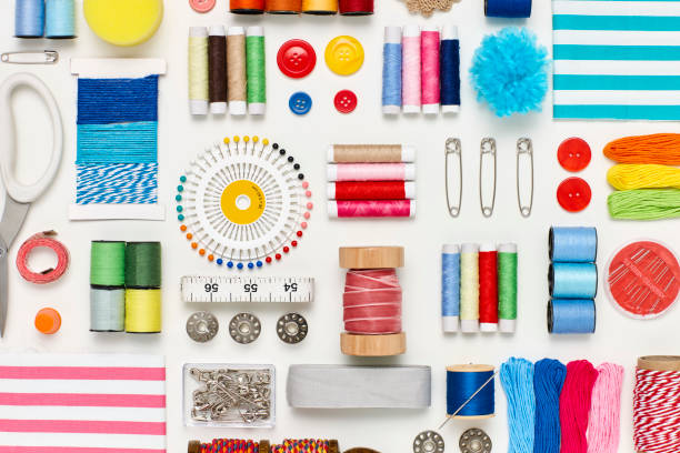 Overhead flat lay of various sewing items on white background Flat lay of various sewing items on white background. Overhead view of art and craft products arranged side by side. Multi colored craft materials representing creativity. thread sewing item stock pictures, royalty-free photos & images