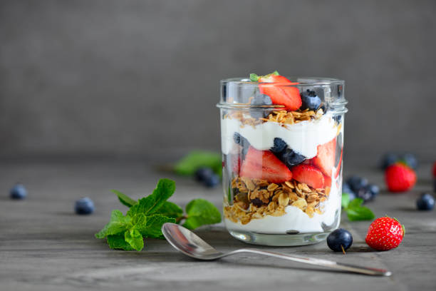 Yogurt with homemade granola Yogurt with fresh blueberries and strawberies and homemade granola, served in glass jar parfait stock pictures, royalty-free photos & images