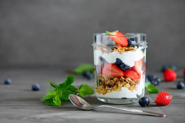 Yogurt with fresh blueberries and strawberies and homemade granola, served in glass jar