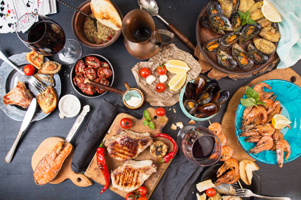 sobrecarga de mesa de jantar. sortidas delicioso churrasco grelhado carne e frutos do mar com legumes. carne de porco grelhado bife grelhada salmão, truta, mexilhões, camarões, tomate seco, tomate cereja, chilii pimenta, vidro de videira vermelha. conceito de partido do piquenique churrasco - barbecue meal seafood steak - fotografias e filmes do acervo