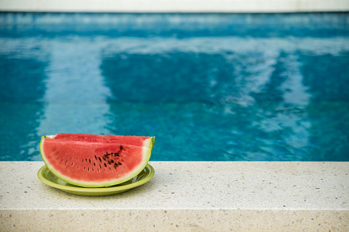 Red watermelon at swimming pool. Copy Space