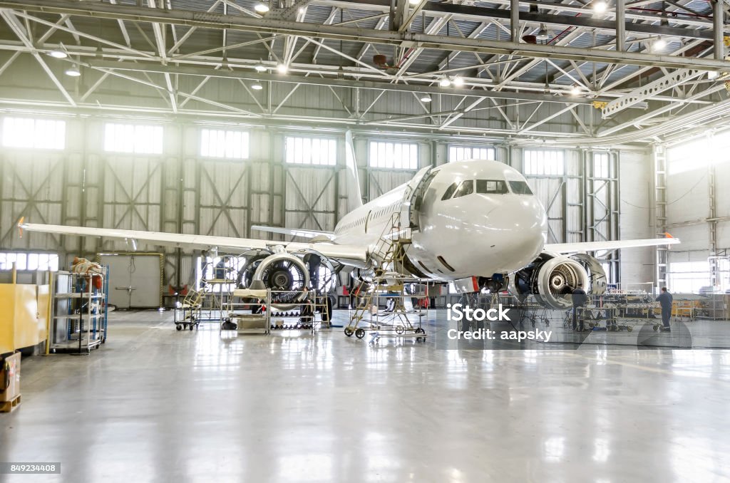 Passenger aircraft on maintenance of engine and fuselage repair in airport hangar Repairing Stock Photo