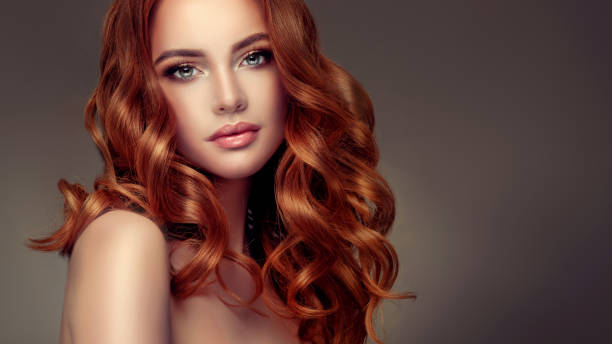 Red haired woman with voluminous, shiny and curly hairstyle.Flying hair. stock photo