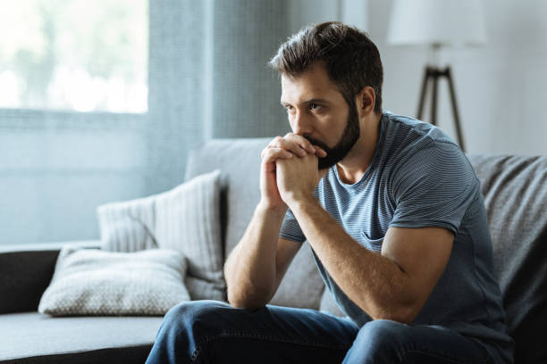 istock Unhappy bearded man sitting on the sofa 849235492